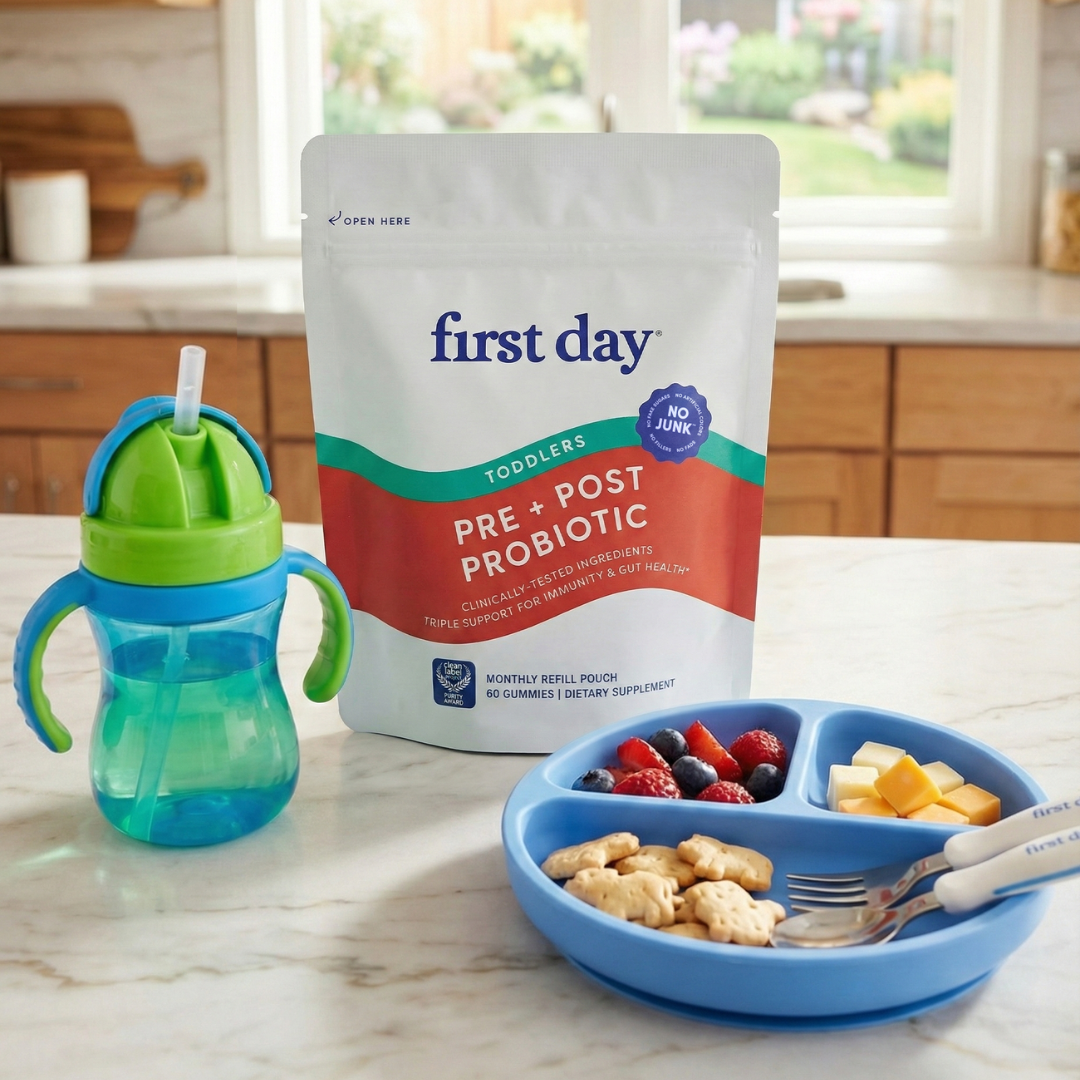 Probiotic package, sippy cup, and divided plate with snacks on a kitchen counter.