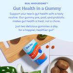 A bottle of Teens' 3-in-1 Pre+ Post+ Probiotic sits on a wooden board with two brown gummies, surrounded by sliced and whole kiwis, against a light blue background. Text highlights gummies for teen digestive health and immune support.