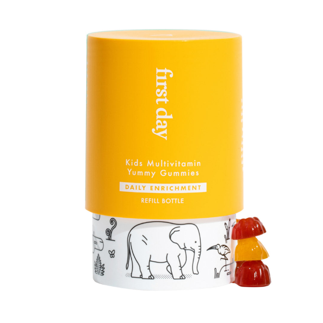 A yellow and white container labeled Kids Enrichment stands next to three stacked, colorful bear-shaped gummy vitamins. The bottle features animal illustrations, including an elephant.