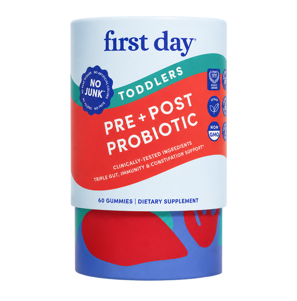 A cylindrical container of First Day Toddlers Pre + Post Probiotic dietary supplement gummies, featuring a white label with red and green accents and a blue base.