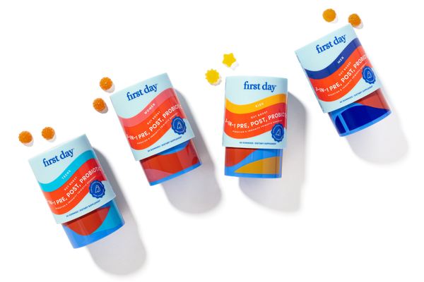 Four bottles of 'first day' product with colorful labels on a white background