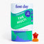 A cylindrical container of First Day The Multi dietary supplement gummies for toddlers, shown on a clean white background with a small red and orange star-shaped gummy candy placed in front of the container.