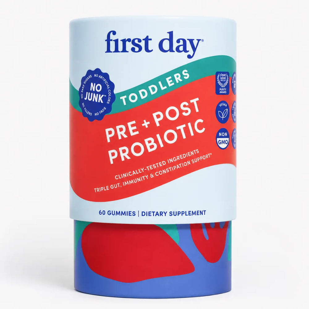 A cylindrical container of First Day Toddlers Pre + Post Probiotic gummies, featuring a white label with bold red and green graphic elements and blue branding.